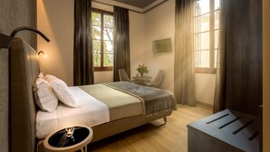 A bedroom with a bed, bedside table, chair, and a small table with a vase. - Tourist House Liberty (Florence)