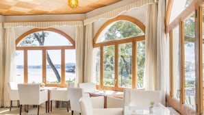 A room with a view of the beach, featuring white furniture and large windows. - Hotel Cala Fornells (Calvia)