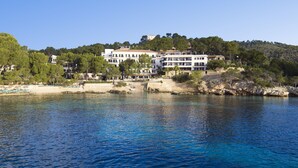 A coastal hotel with multiple buildings, a beach, and rocky terrain. - Hotel Cala Fornells (Calvia)