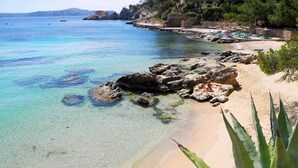 Una playa costera con aguas turquesas cristalinas, formaciones rocosas y un litoral arenoso.