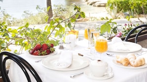 A table set for breakfast with a view of the sea, including plates, glasses, and a bowl of strawberries. - Hotel Cala Fornells (Calvia)