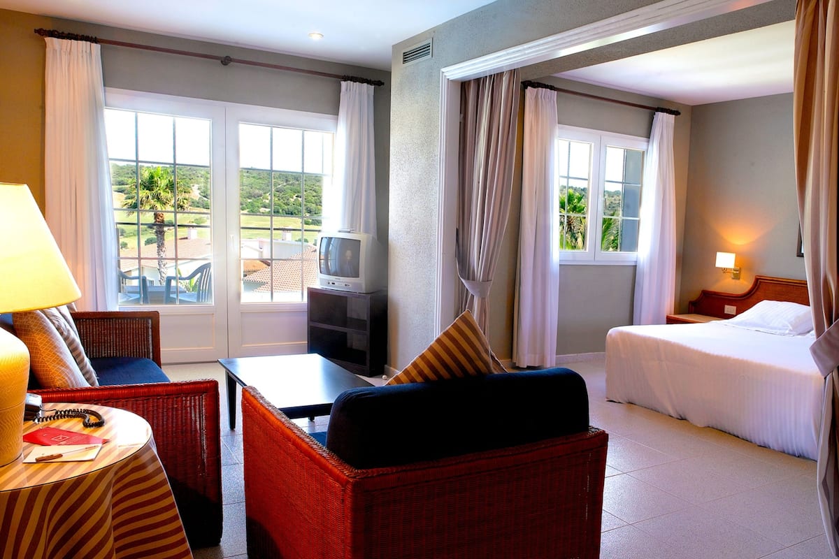 Una habitación de hotel con una cama, televisión, mesa de comedor y una silla.