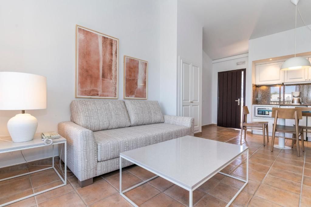 Un salon moderne avec un canapé, une table basse, une lampe et des œuvres d’art accrochées au mur.