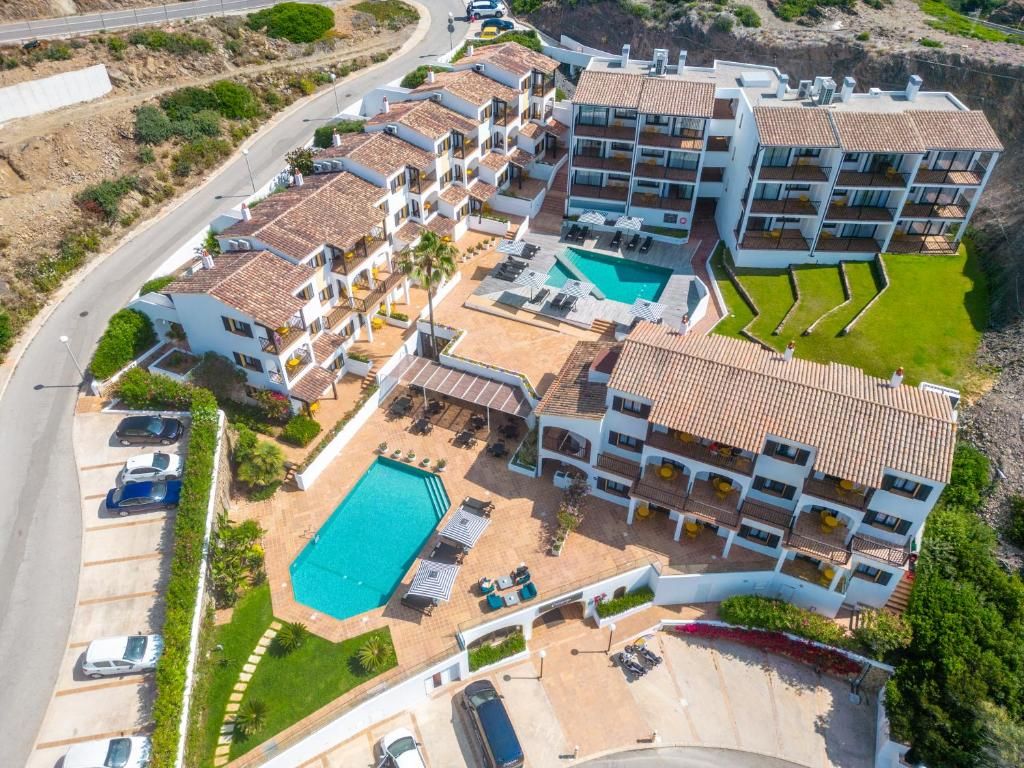 Un hotel de varios pisos con piscina, varios balcones y un estacionamiento.