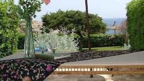 An outdoor patio area with a table, chairs, and a large umbrella. - Apartamentos Parque Mar (Santanyi)