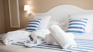 Una cama bien hecha con ropa de cama azul y blanca a rayas, almohadas blancas y cabecera blanca.
