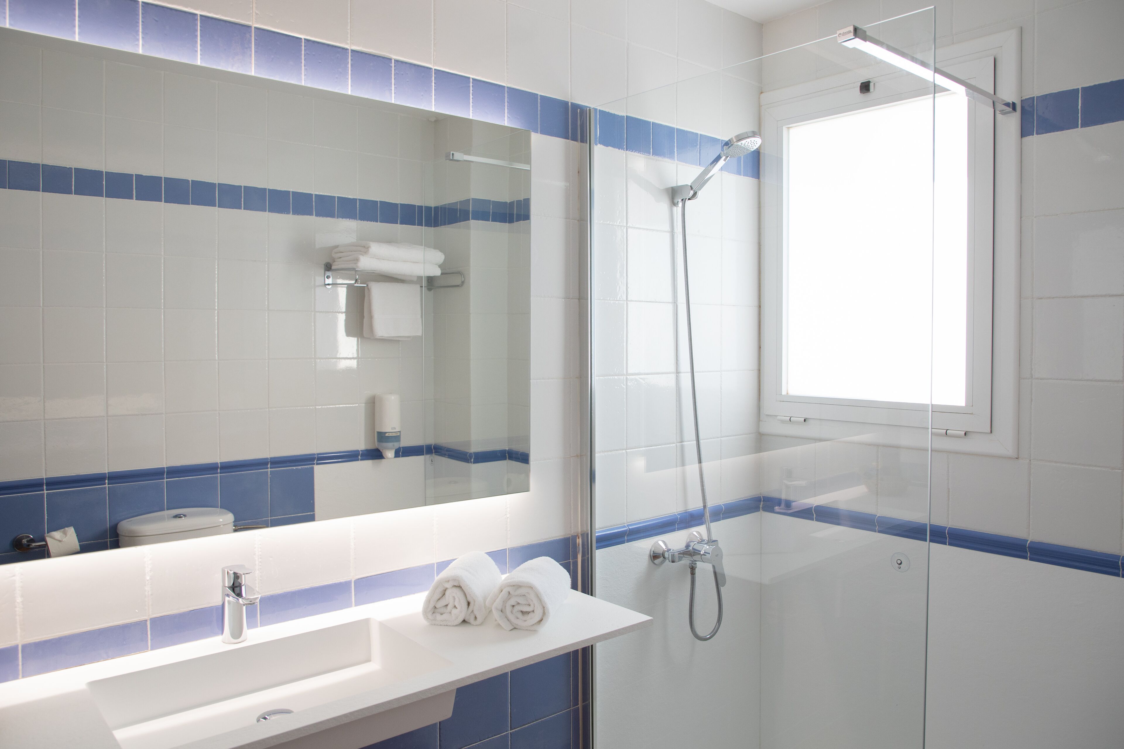 Un baño con un lavamanos blanco, un espejo y una ducha.