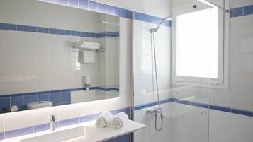 Un baño con un lavamanos blanco, un espejo y una ducha.