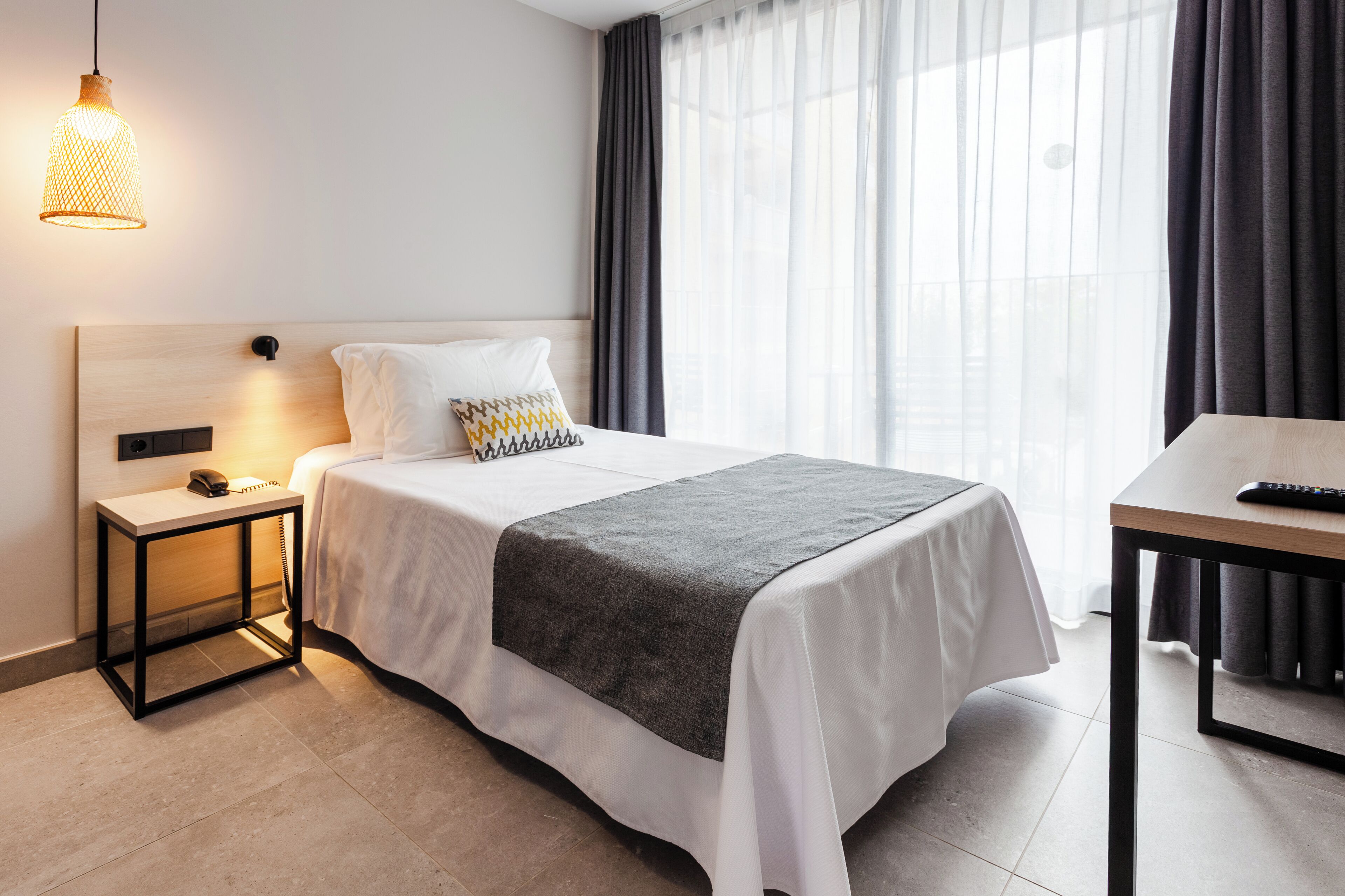 Une chambre d’hôtel avec un lit, une table de chevet, une lampe et une vue sur l’extérieur.