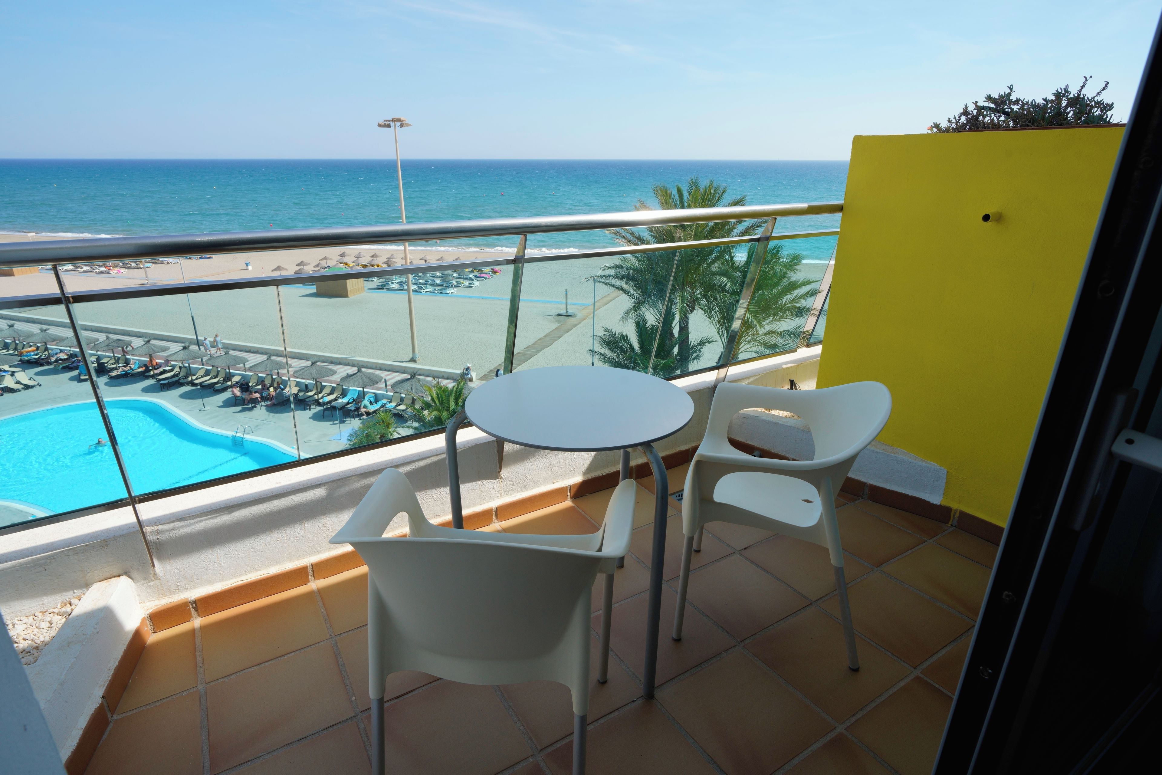 Un balcón con piscina, sillas y vistas a la playa.