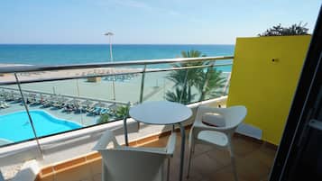 Un balcón con piscina, sillas y vistas a la playa.