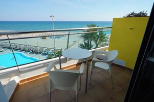 Un balcón con piscina, sillas y vistas a la playa.
