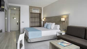 Una habitación de hotel moderna con cama, sofá, mesa de comedor y televisión.