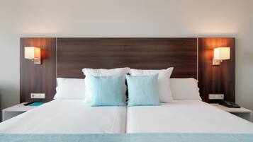 Habitación de hotel con una cama grande, dos mesitas de noche, un teléfono y dos lámparas fijadas a la pared.