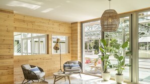 Un interior moderno con paredes de madera, un sillón de mimbre, una mesa redonda y ventanas amplias.