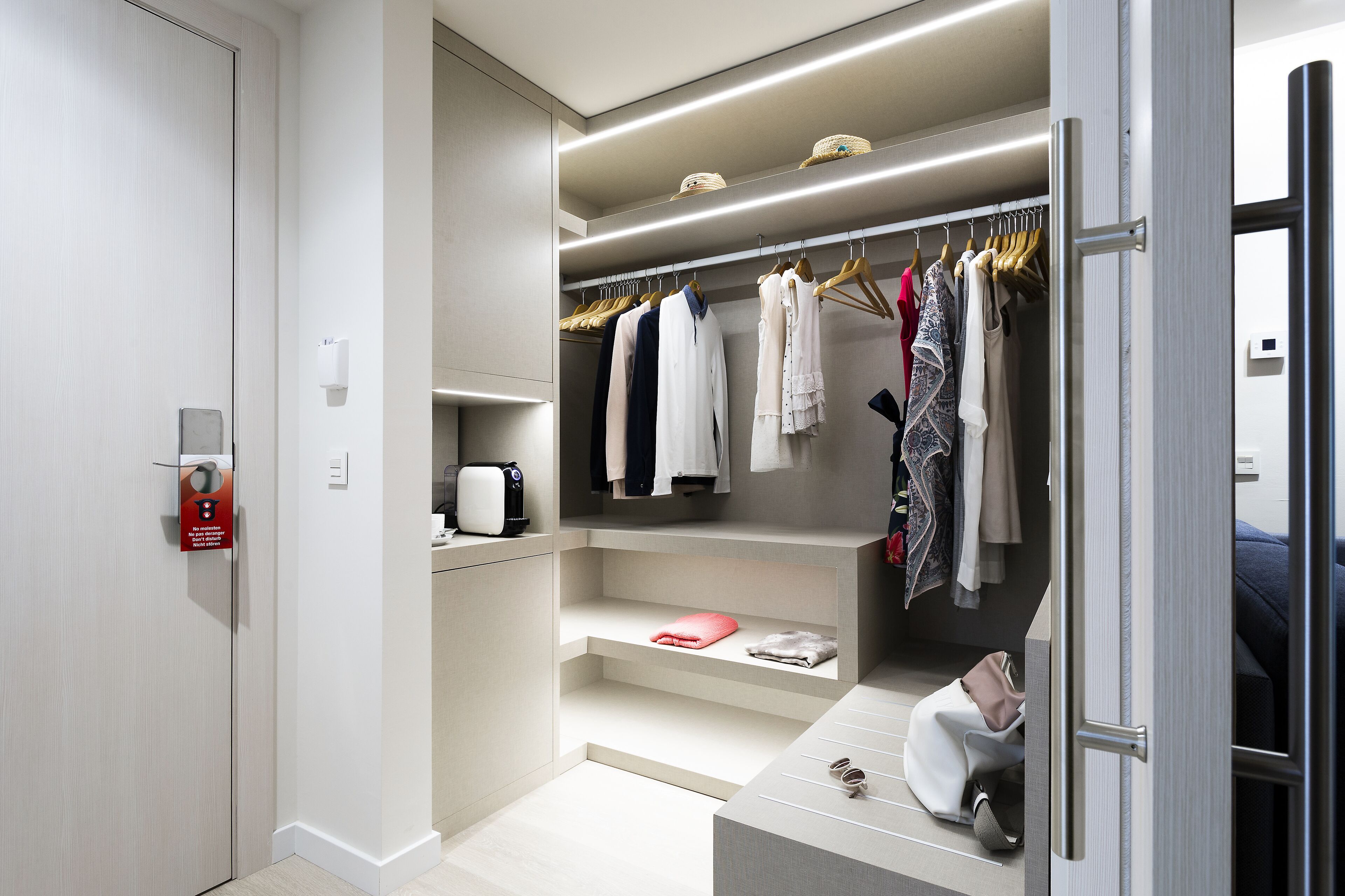 Een moderne kast met hangende kleding, planken en een verhoogd zitgedeelte.