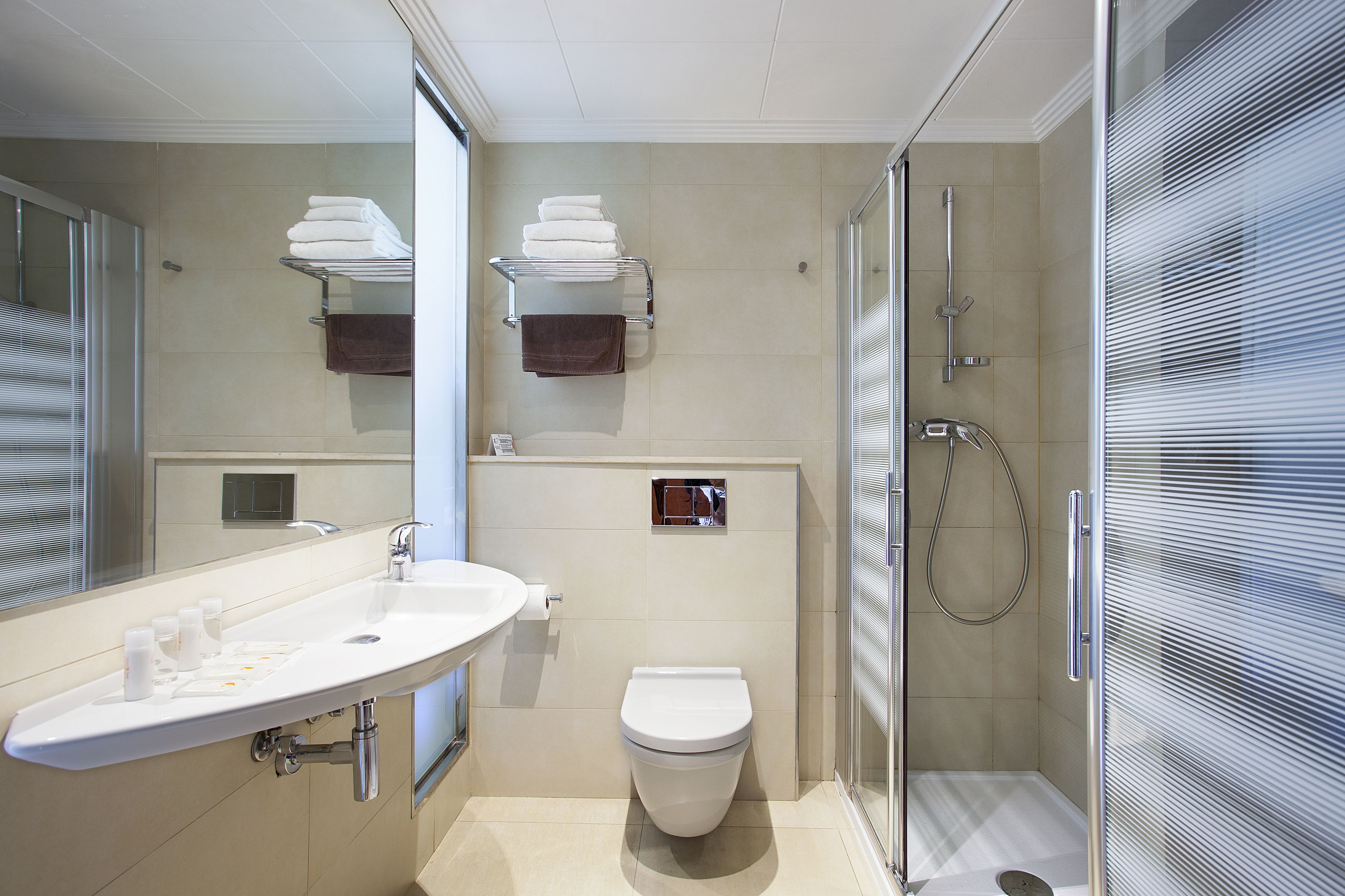 Une salle de bain moderne équipée d’un lavabo, de toilettes et d’une douche.