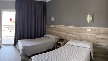 A hotel room with two beds, a wooden headboard, a nightstand with a phone, and a view of the outside.