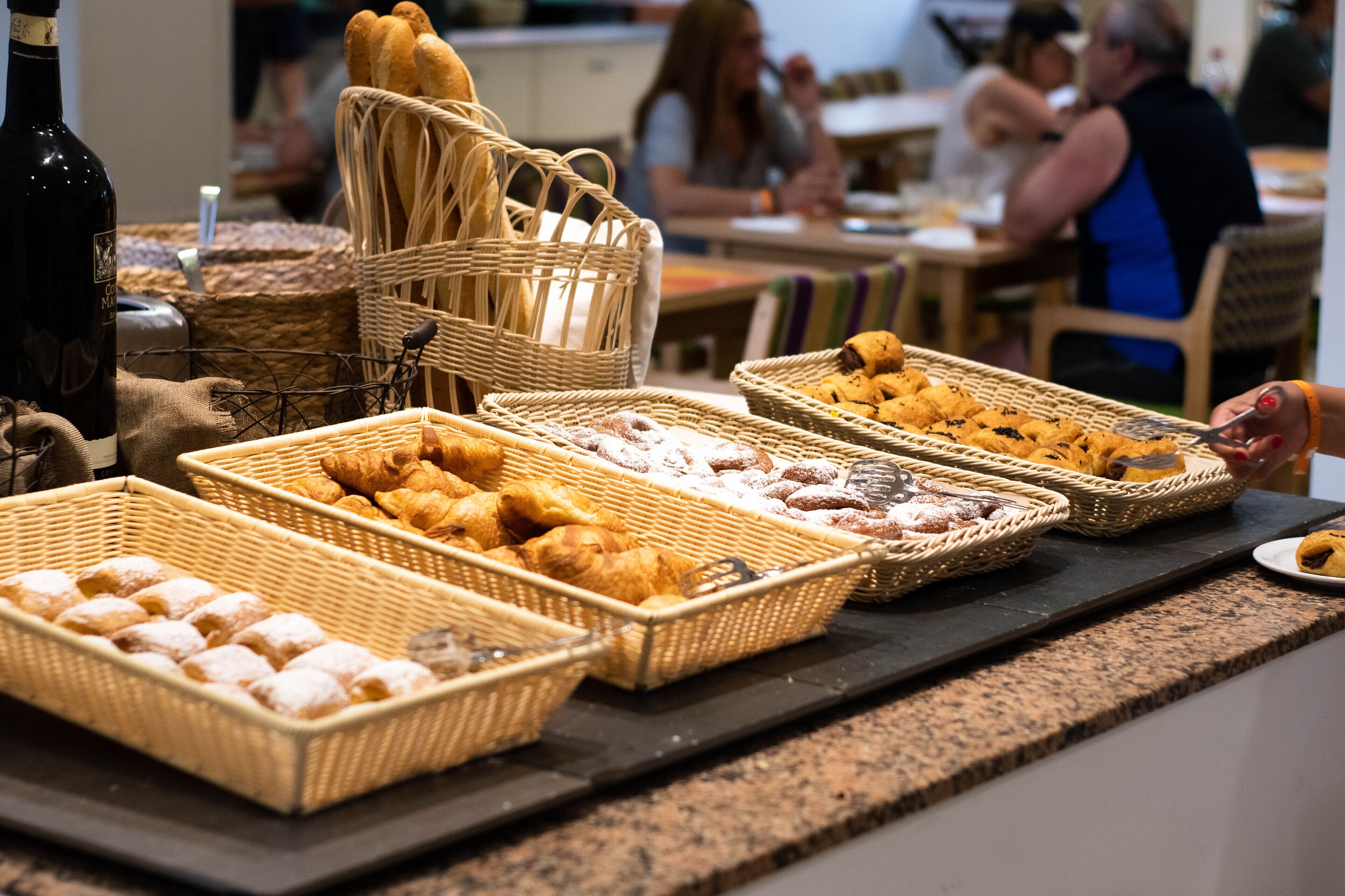 Un bufé con diversas opciones de pastelería y cestas de pan.