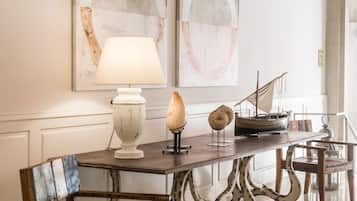 A dining area with a table set for two, featuring a white lamp, decorative items, and a ship model.