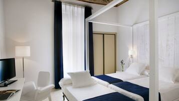 A hotel room with two beds, a desk with a computer, a chair, and a television.