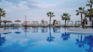 Una piscina al aire libre, sombrillas, tumbonas