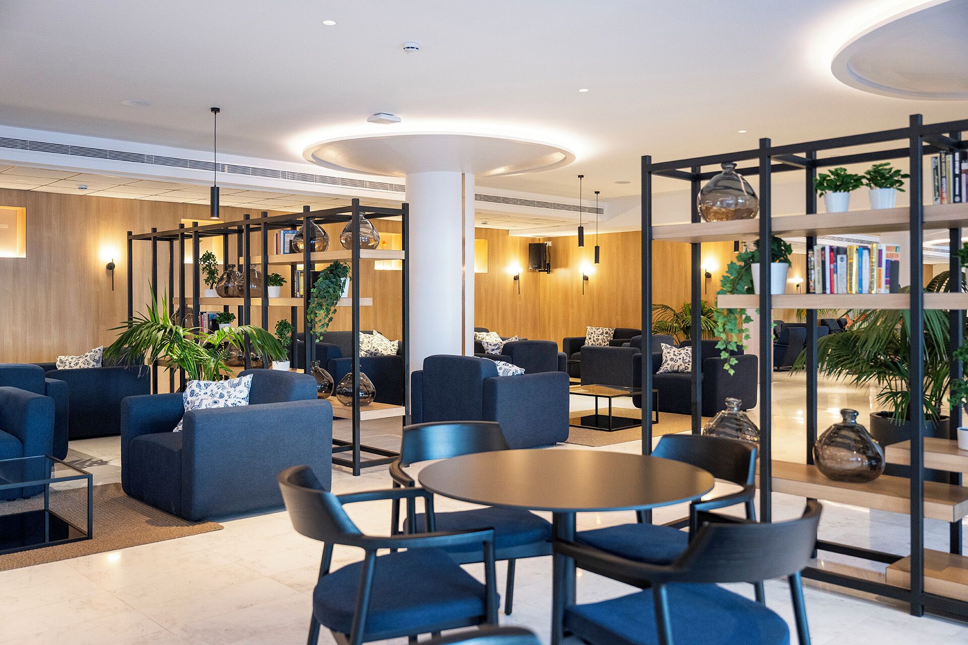 A modern lounge area with sofas, a coffee table, and bookshelves.