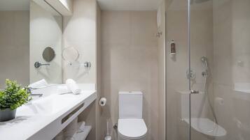 Un bany modern amb dutxa envidrada, un lavabo blanc amb mirall i un vàter.