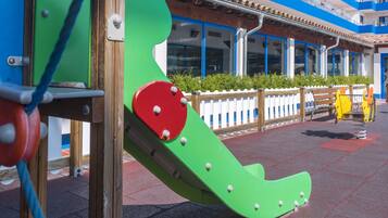 Une aire de jeux avec un toboggan vert et une balançoire jaune.