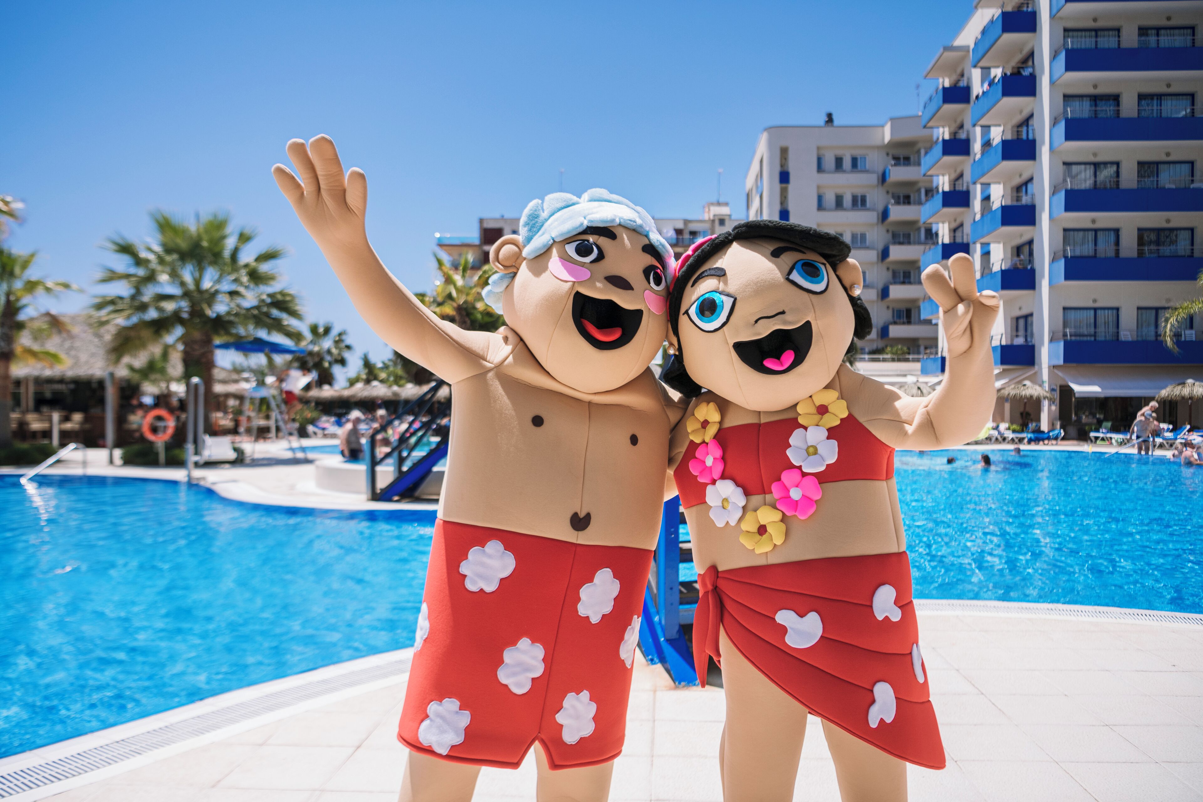 Two characters in swimwear by a pool with a building in the background.