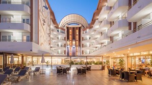 A hotel atrium with multiple floors, a central open space with seating, and a large mural on the left wall. - ALEGRIA Florida Park (Santa Susanna)