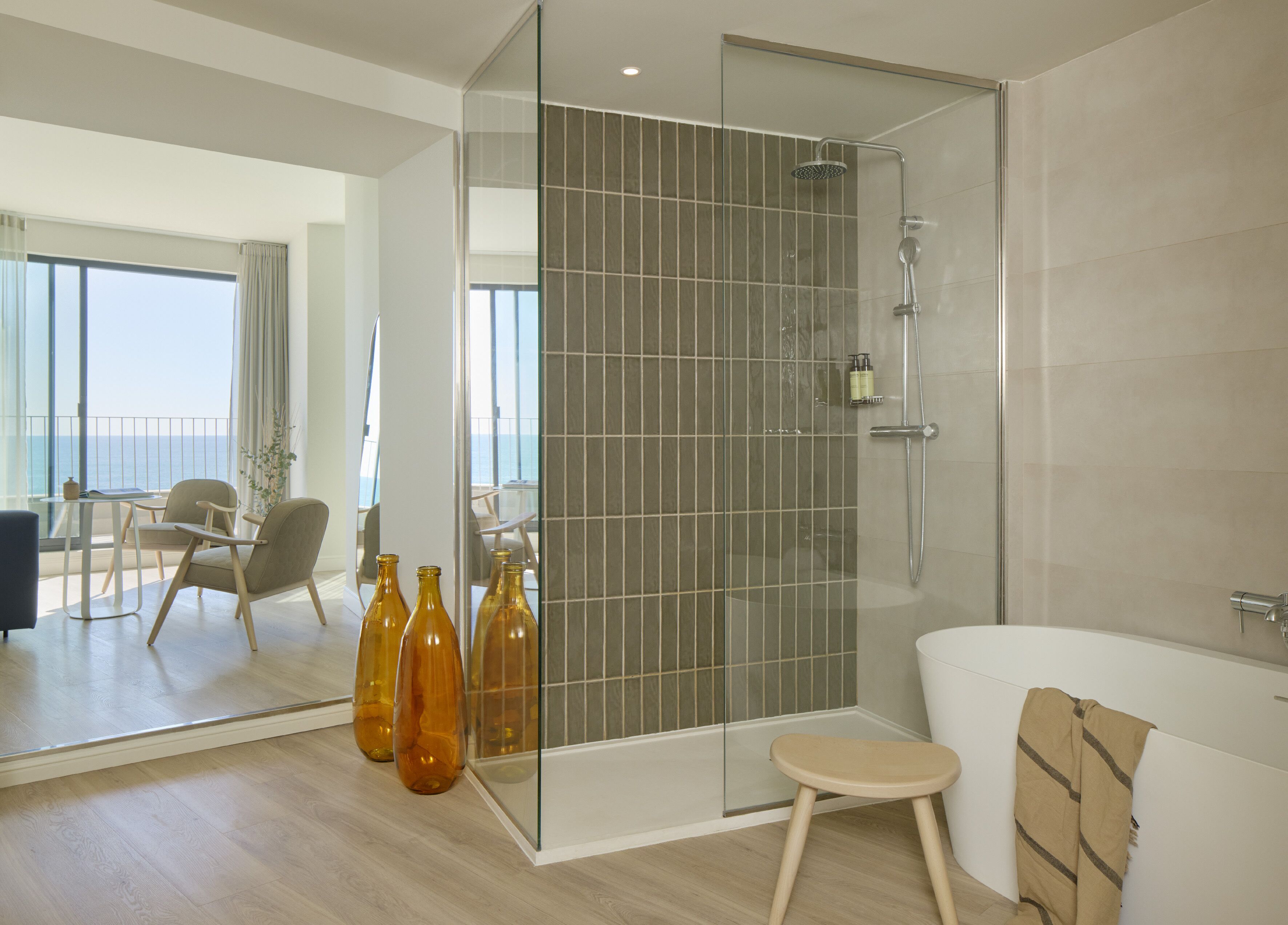 Ein modernes Badezimmer mit einer gläsernen Dusche, einer Badewanne und einem kleinen Hocker.