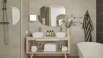 Et moderne badeværelse med et fritstående badekar, et toiletbord med to håndvaske, et stort spejl og en bruseniche.