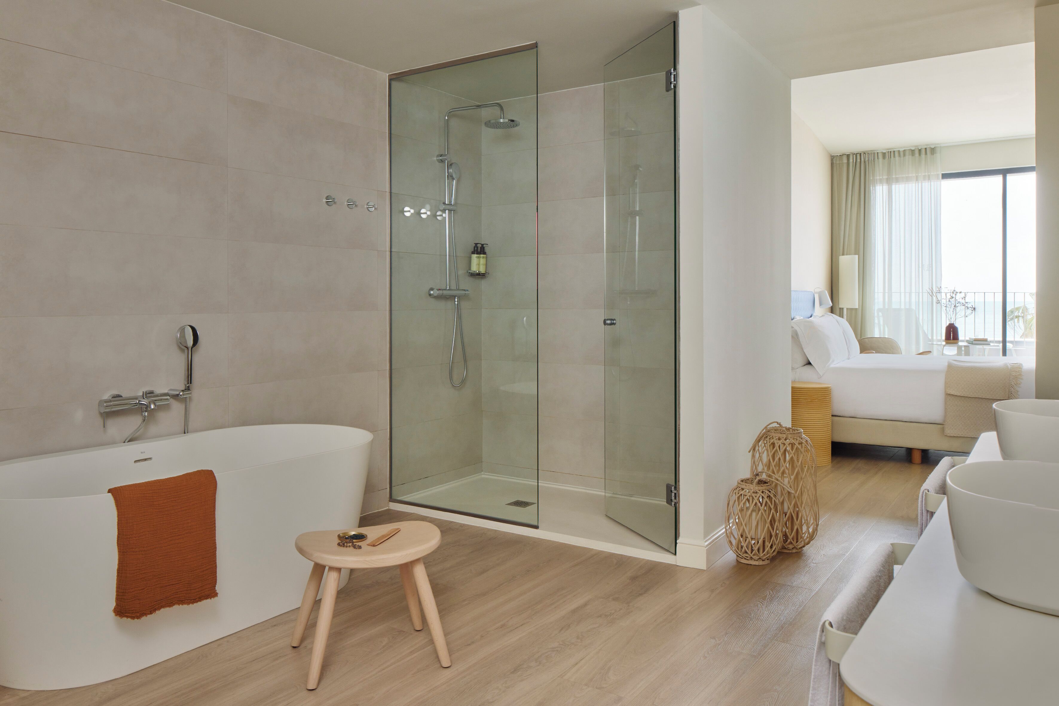 Ein modernes Badezimmer mit einer gläsernen Duschkabine, einer freistehenden Badewanne und einem kleinen Hocker.