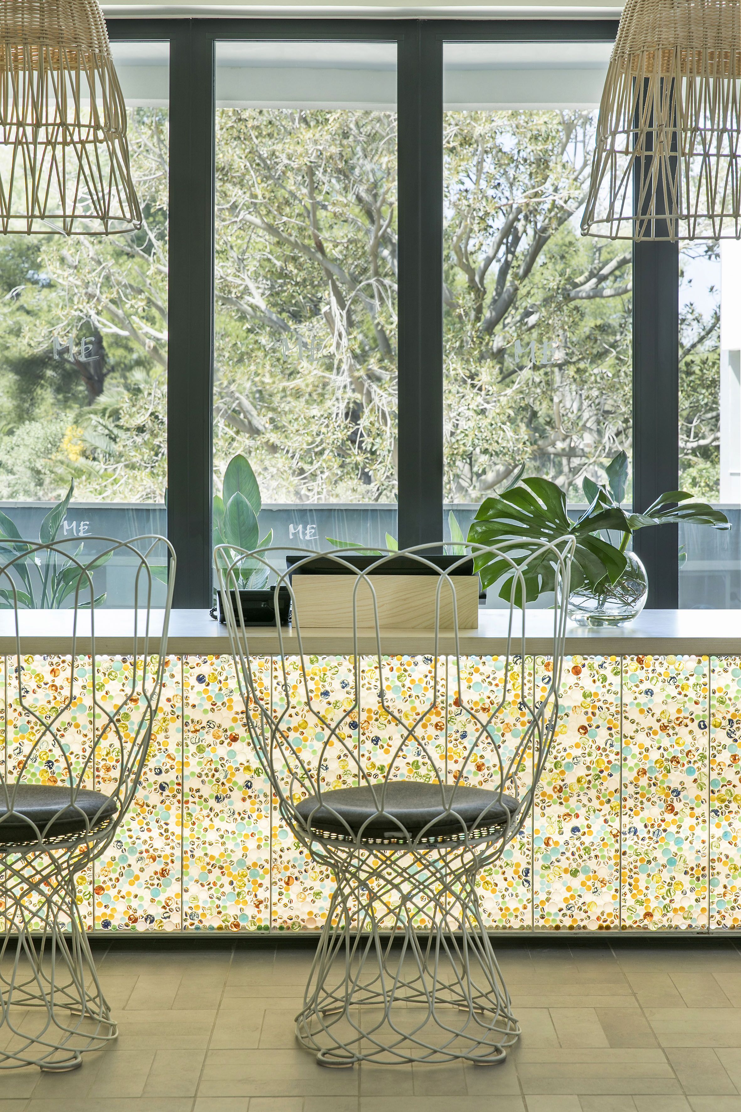 Un interior moderno con tres sillas de estructura metálica, una mesita y una planta en maceta.