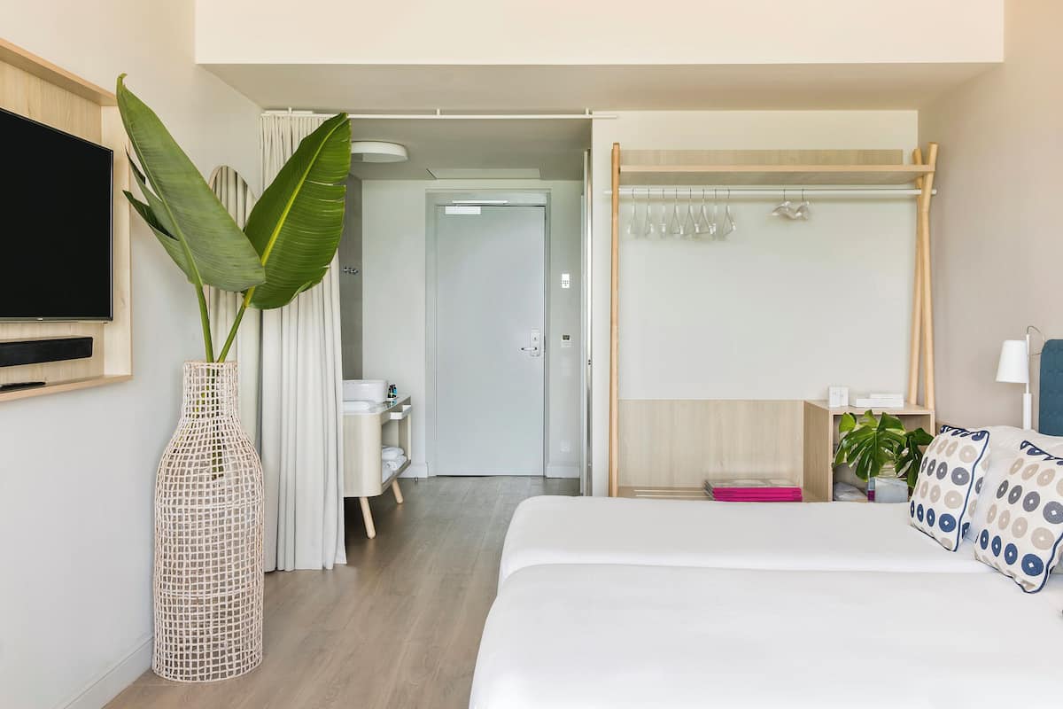 Ein Hotelzimmer mit Bett, Fernseher, Pflanze und Duschbereich.