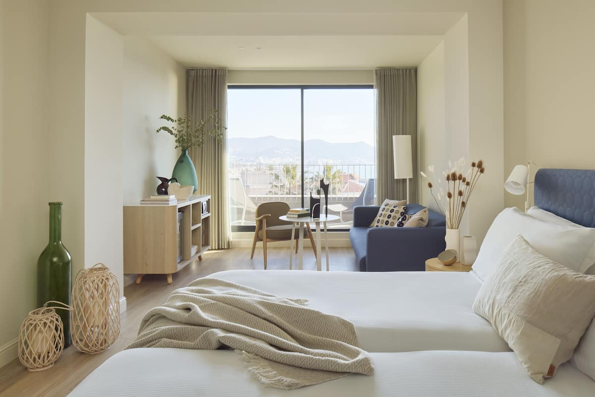 Ein Hotelzimmer mit einem großen Bett, einer Couch, einem Balkon mit Blick und einem kleinen Tisch.