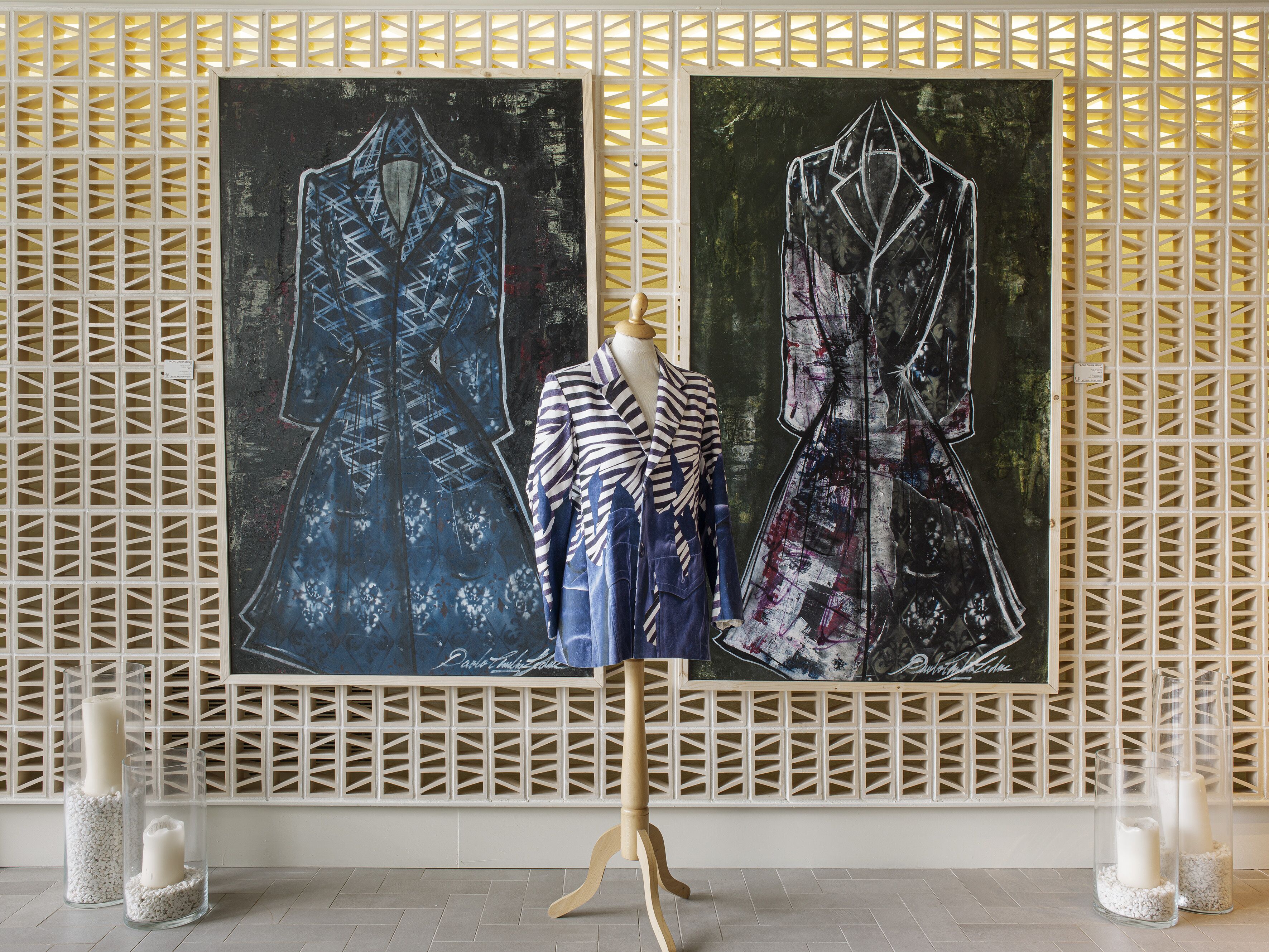 A mannequin displaying two dresses against a wall with a geometric pattern.