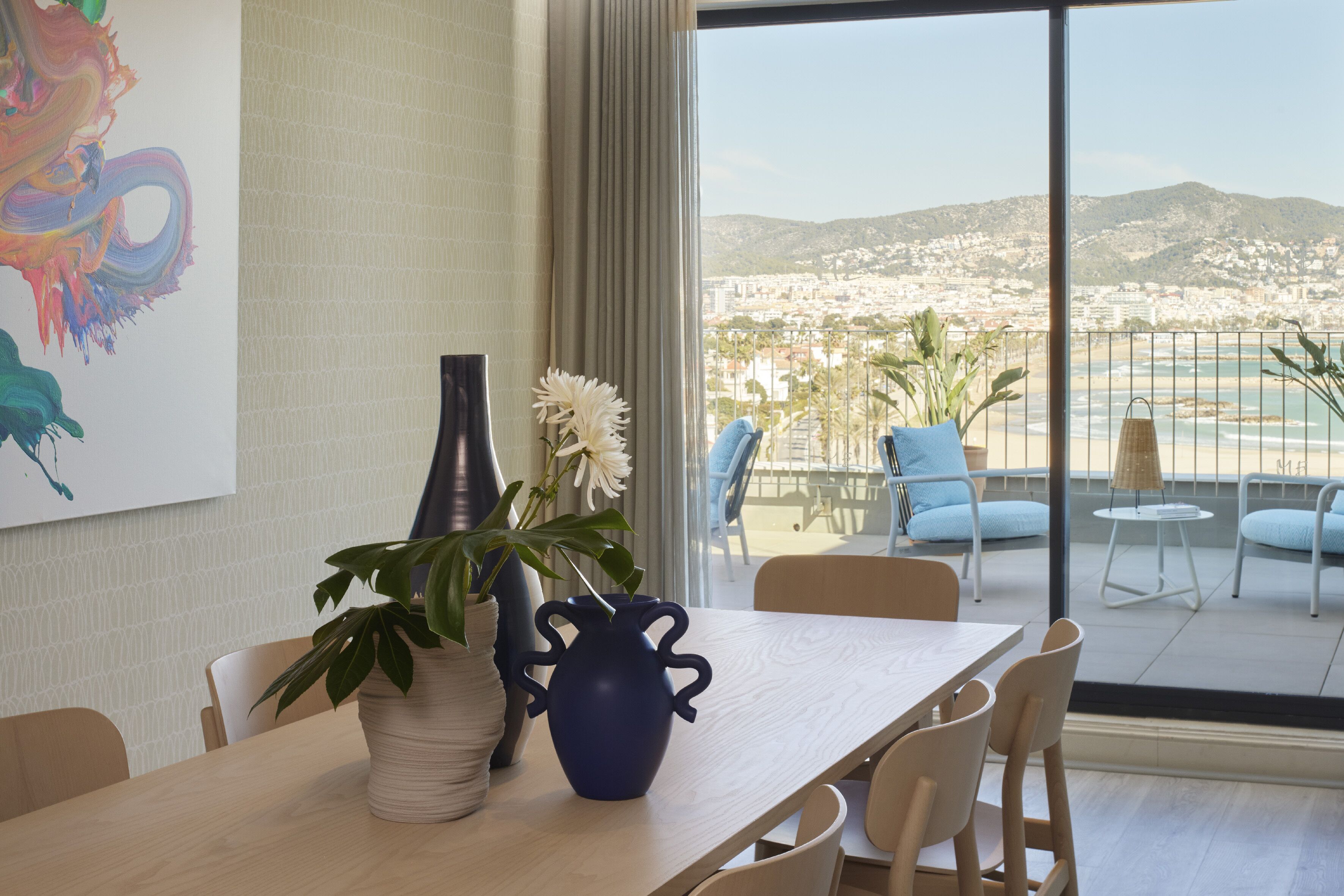A dining area with a table, chairs, a vase, and a plant.