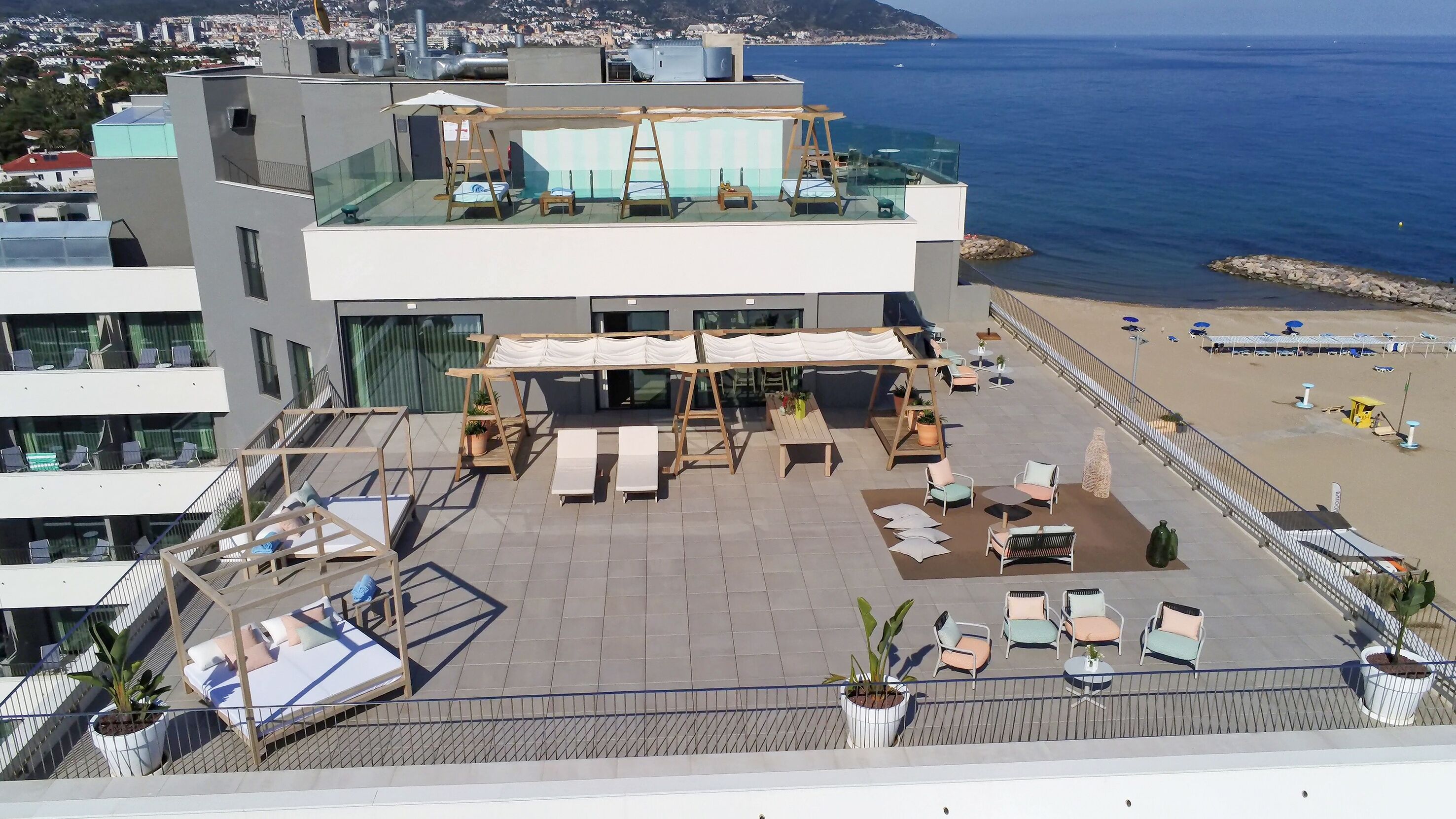 A rooftop terrace with outdoor seating, a pool, and a view of the sea.
