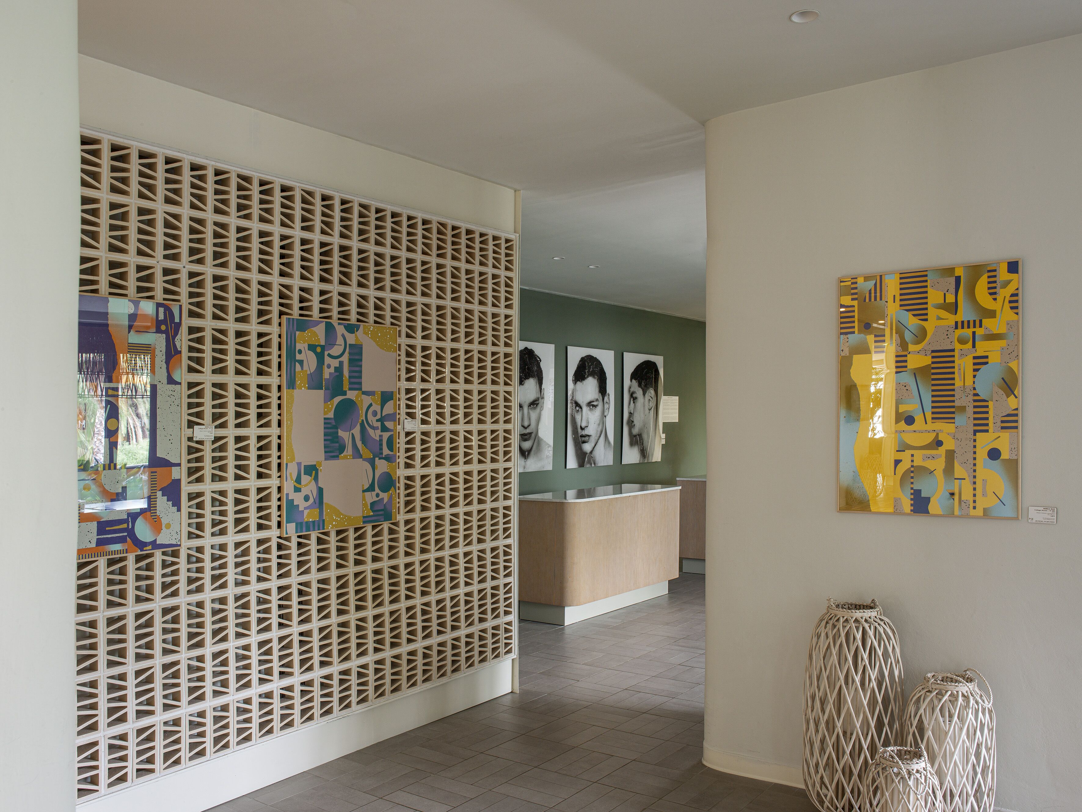A modern interior with a geometric patterned wall, a reception desk, and abstract art on the walls.