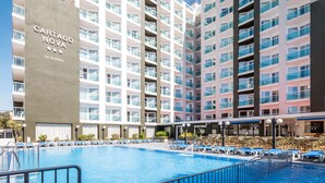 Un hotel moderno con piscina y tumbonas.