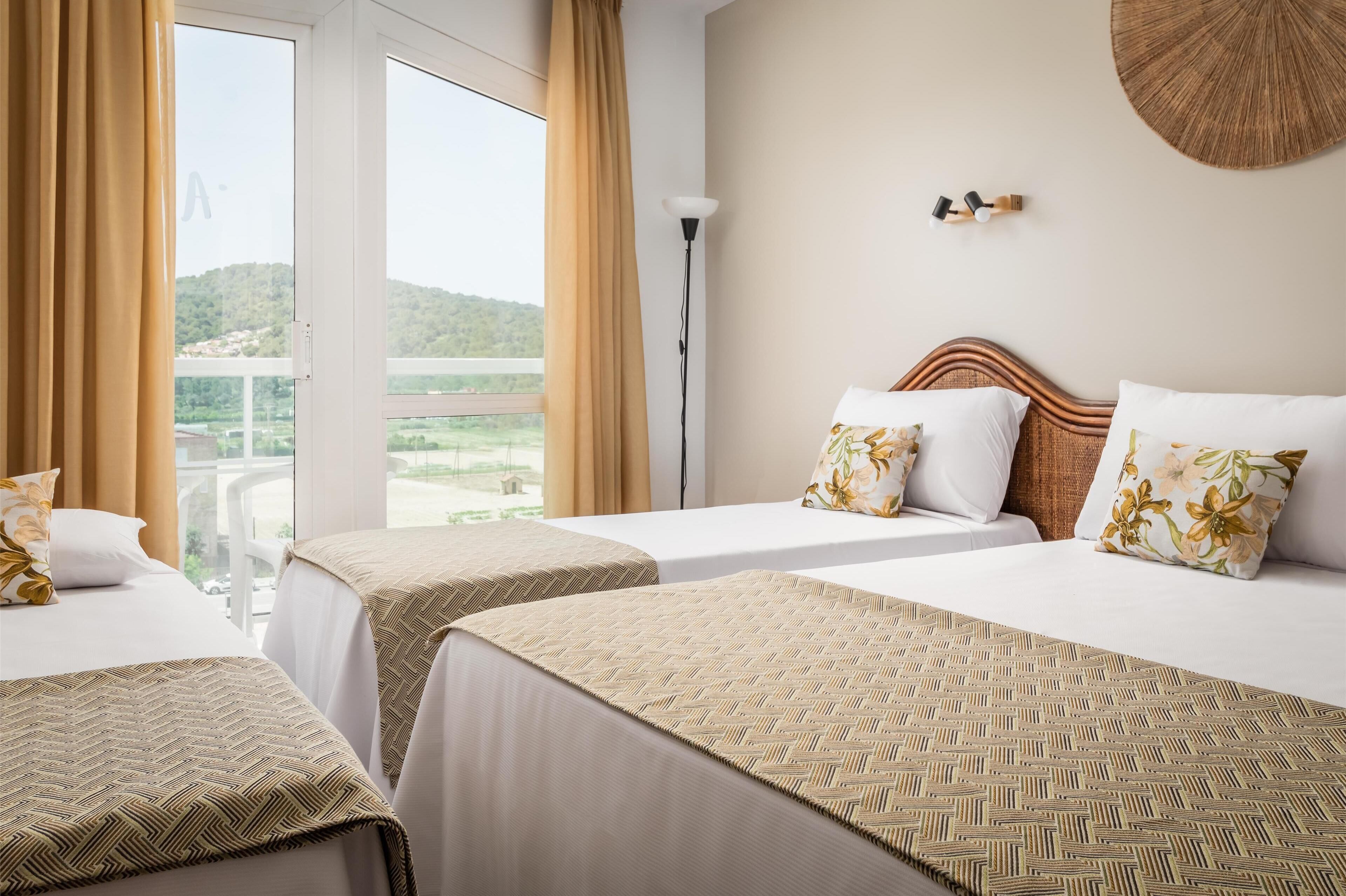 Habitación de hotel con dos camas, vistas al campo y una lámpara.