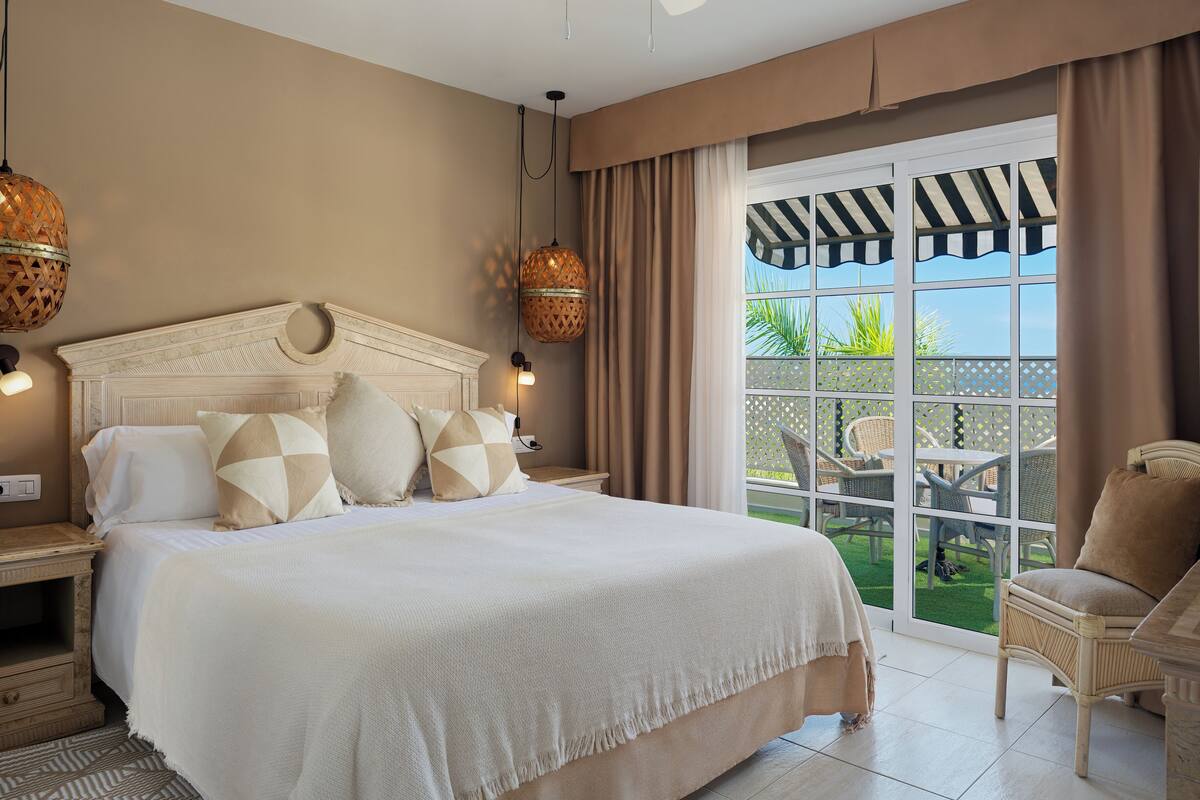 A spacious bedroom with a large bed, a ceiling fan, and a view of the outdoor patio.