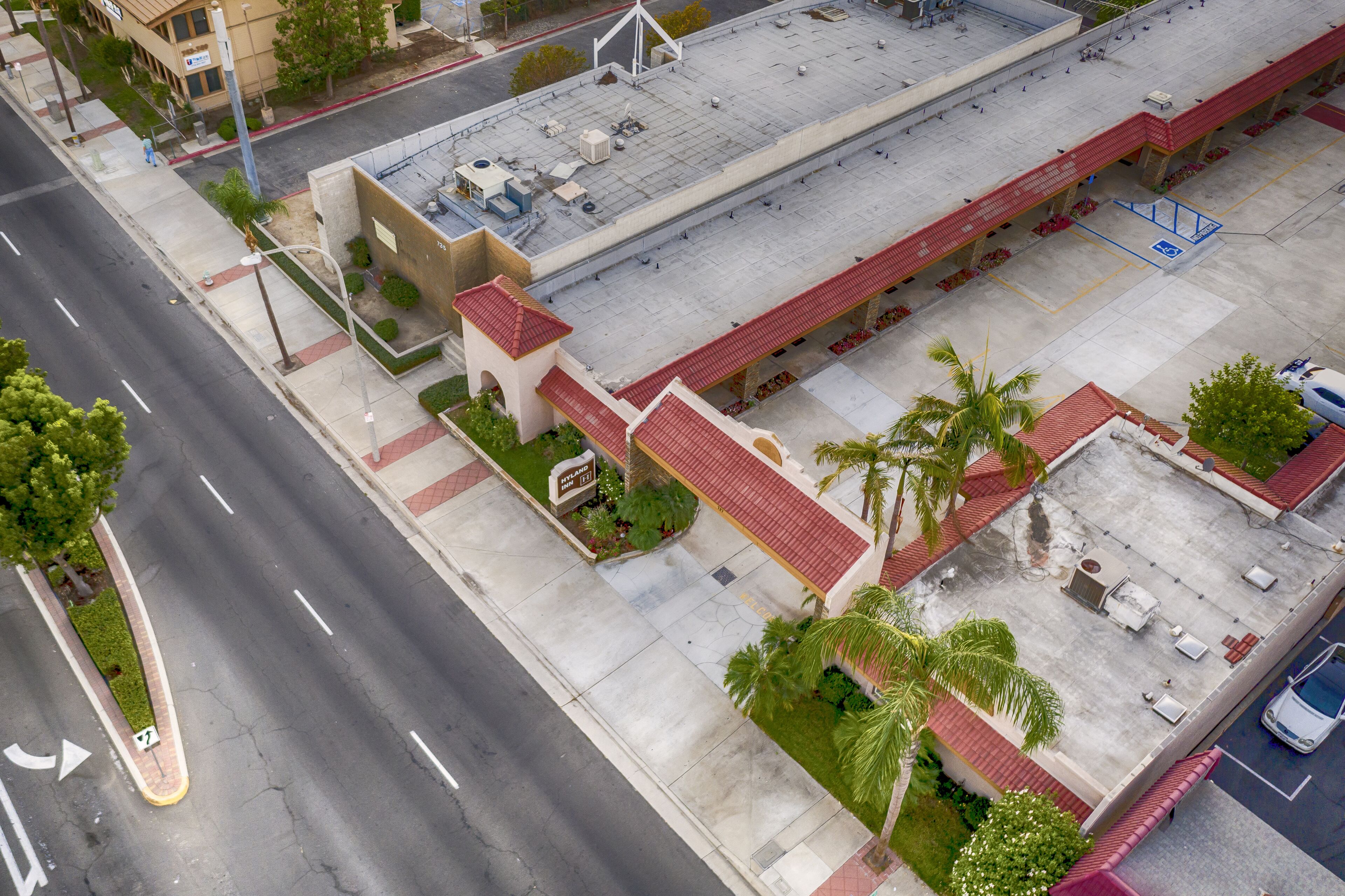 An aerial view of a parking lot adjacent to a building with a red roof and a sign indicating a restaurant.
