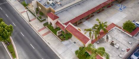 An aerial view of a parking lot adjacent to a building with a red roof and a sign indicating a restaurant.