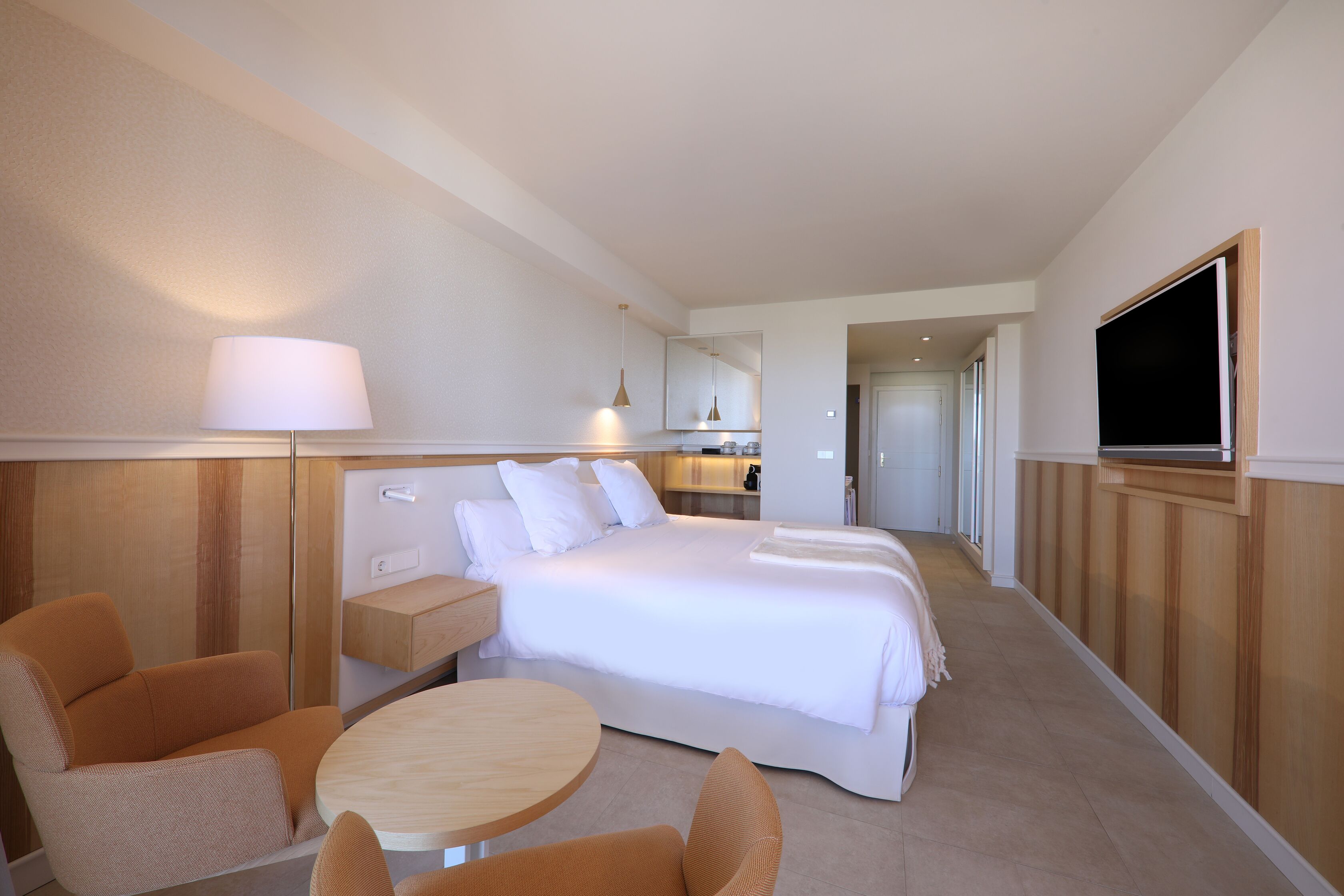 Una habitación de hotel con una cama grande, un escritorio, una silla, una mesa y un televisor.
