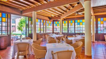 Un restaurante con vigas de madera, sillas de mimbre y mesas dispuestas para comer.