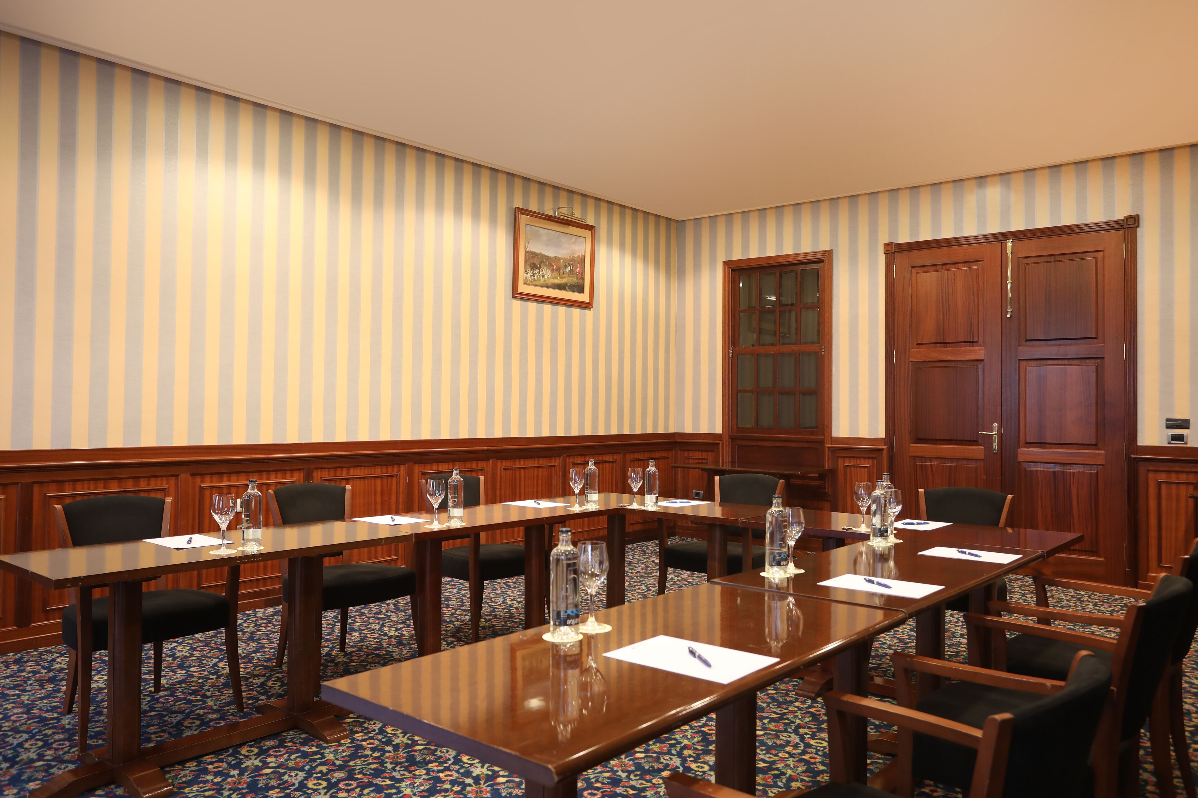Un salón de conferencias con una larga mesa, sillas y un cuadro en la pared.
