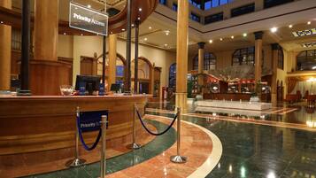 A spacious lobby with a marble floor, a reception desk, and a 'Priority Access' sign.